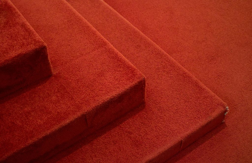 Detailed view of red carpeted stairs, highlighting texture and design.